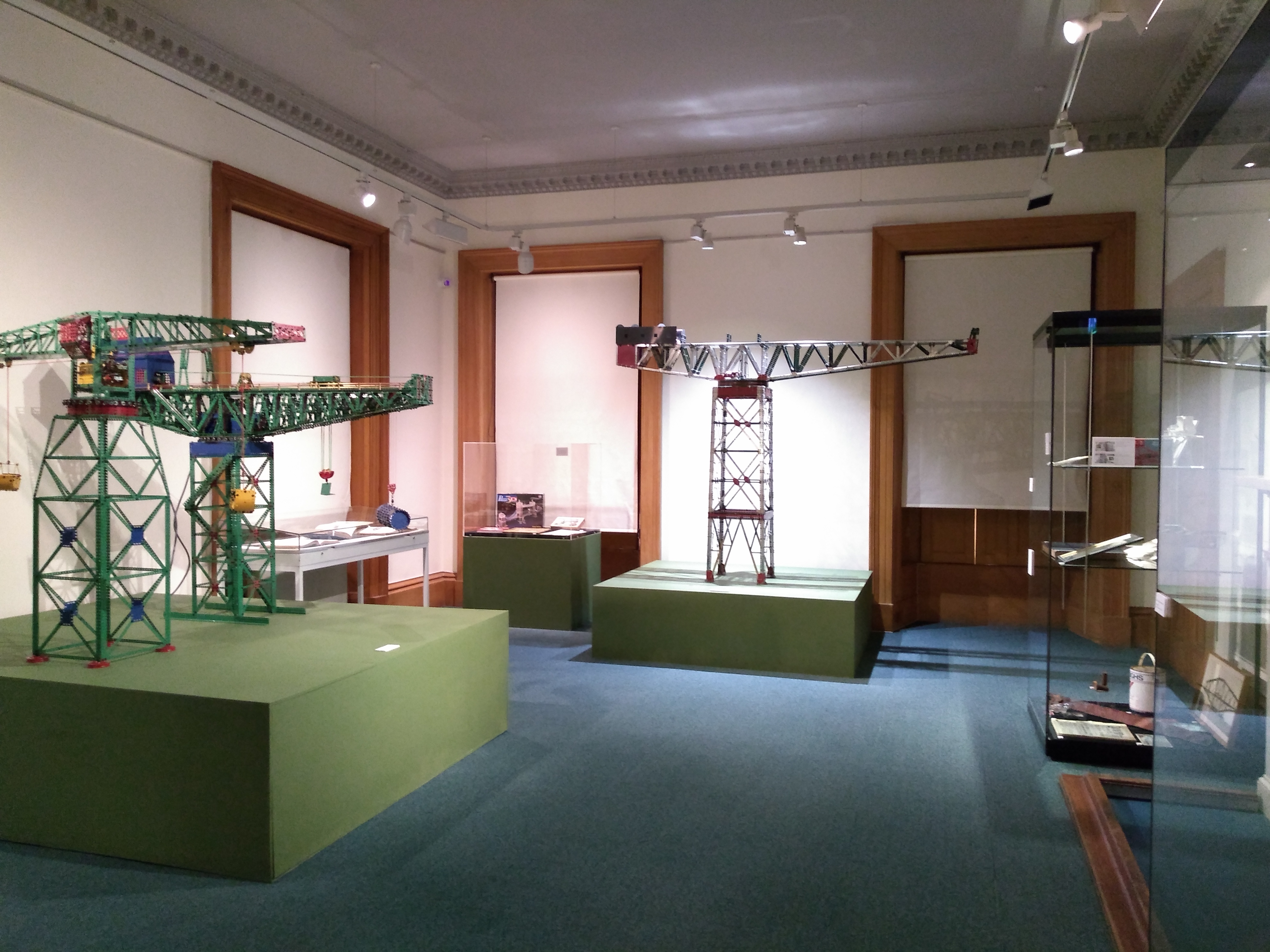 View of gallery with three large Meccano models of cranes and display cases filled with Arrol-related artefacts
